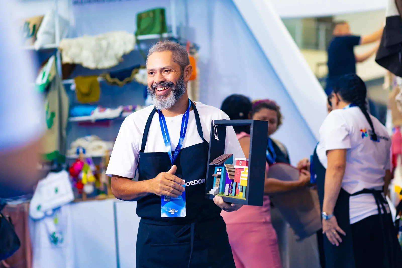 Expositor sorridente em seu estande na Feira do Empreendedor